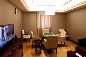 Une chambre d’hôtel équipée d’une télévision, d’une table de billard et de quatre chaises.