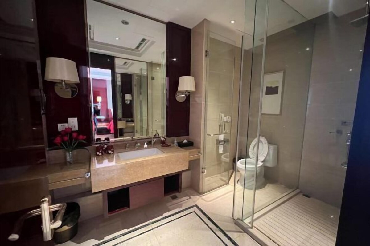 Ein modernes Badezimmer mit einer gläsernen Duschkabine, einem geräumigen Waschtisch mit Spiegel und einer durch die Scheibe sichtbaren Toilette.