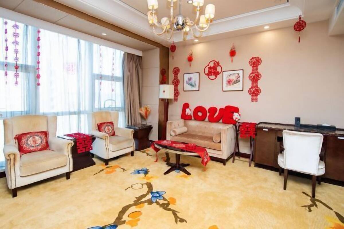 A room with a sofa, chairs, a desk, and a chandelier.