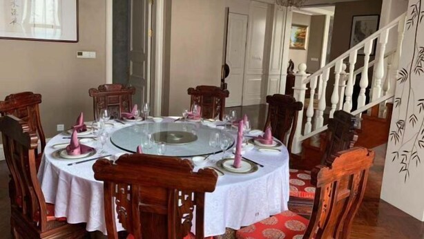 A dining area with a round table, chairs, and a staircase. - Zhongwei International Holiday Hotel (Fushun)
