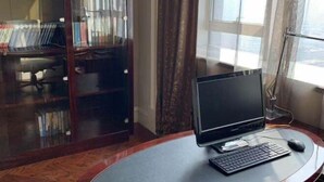 A computer desk with a monitor, keyboard, and mouse, near a window with curtains. - Zhongwei International Holiday Hotel (Fushun)