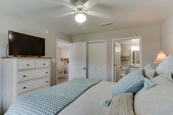A bedroom with a bed, a dresser, a television, a ceiling fan, and a bathroom visible through an open door. - ★ Clean, Beautiful Beach Retreat ★ w/ Semi-Private Beach Access, Chair/Umbrella (Miramar Beach)