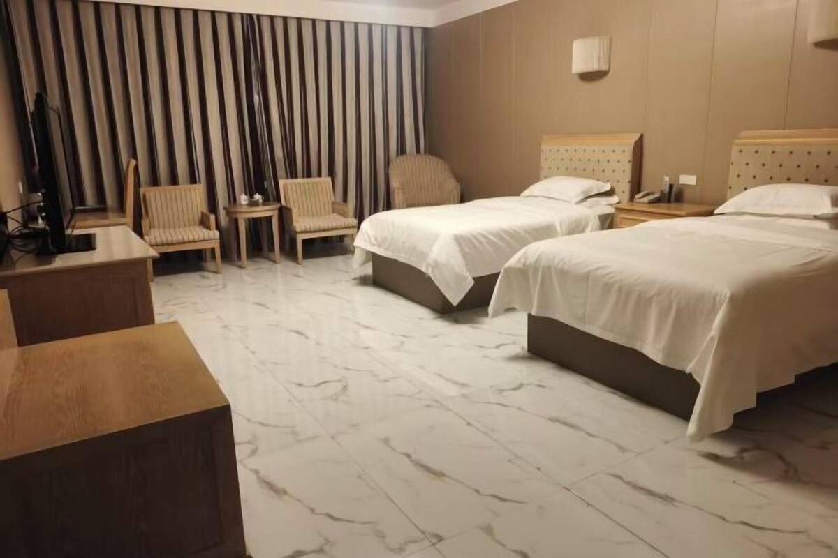 A hotel room with two beds, a desk, and a chair.