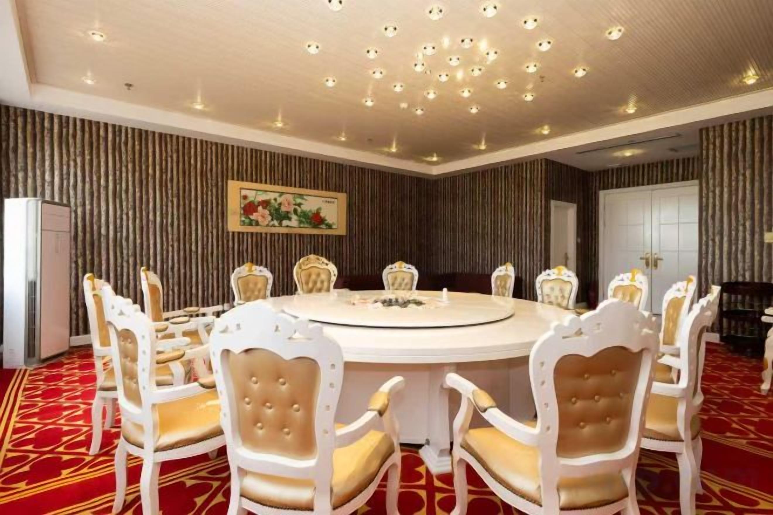 A conference room with a round table and eight chairs, a patterned carpet, and a ceiling with recessed lighting.