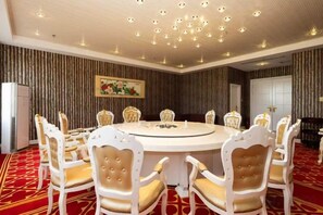 A conference room with a round table and eight chairs, a patterned carpet, and a ceiling with recessed lighting. - Baoshi International Hotel (Antu)