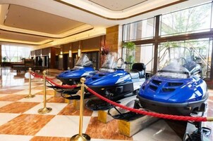 A lobby with a checkered floor, a reception desk, and three blue snowmobiles on display.