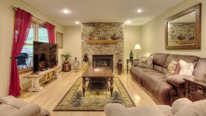 A cozy living room with a stone fireplace, a wooden coffee table, and a brown leather sofa.