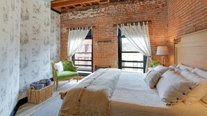 A bedroom with a large bed, a green armchair, and a view through a window. - Elle & Beck`s 2 story suite (Galena)