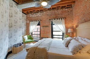 Un dormitorio con una cama grande, un sillón verde y vistas por la ventana.
