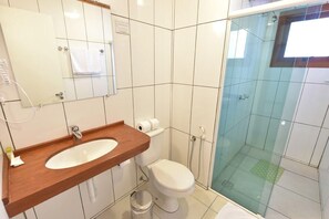 A bathroom with a wooden vanity, a white toilet, and a glass-enclosed shower area. - Hotel Villa Aconchego de Gramado (Gramado)