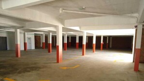 An empty parking garage with white pillars and red bases, yellow directional arrows on the floor, and a concrete ceiling. - Hotel Villa Aconchego de Gramado (Gramado)