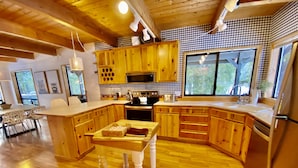 A modern kitchen with wooden cabinets, a central island, and large windows. - Hot tub,pool table,xc/downhill ski,near-Stevens Pass,Leavenworth,Lake Wenatchee (Leavenworth)