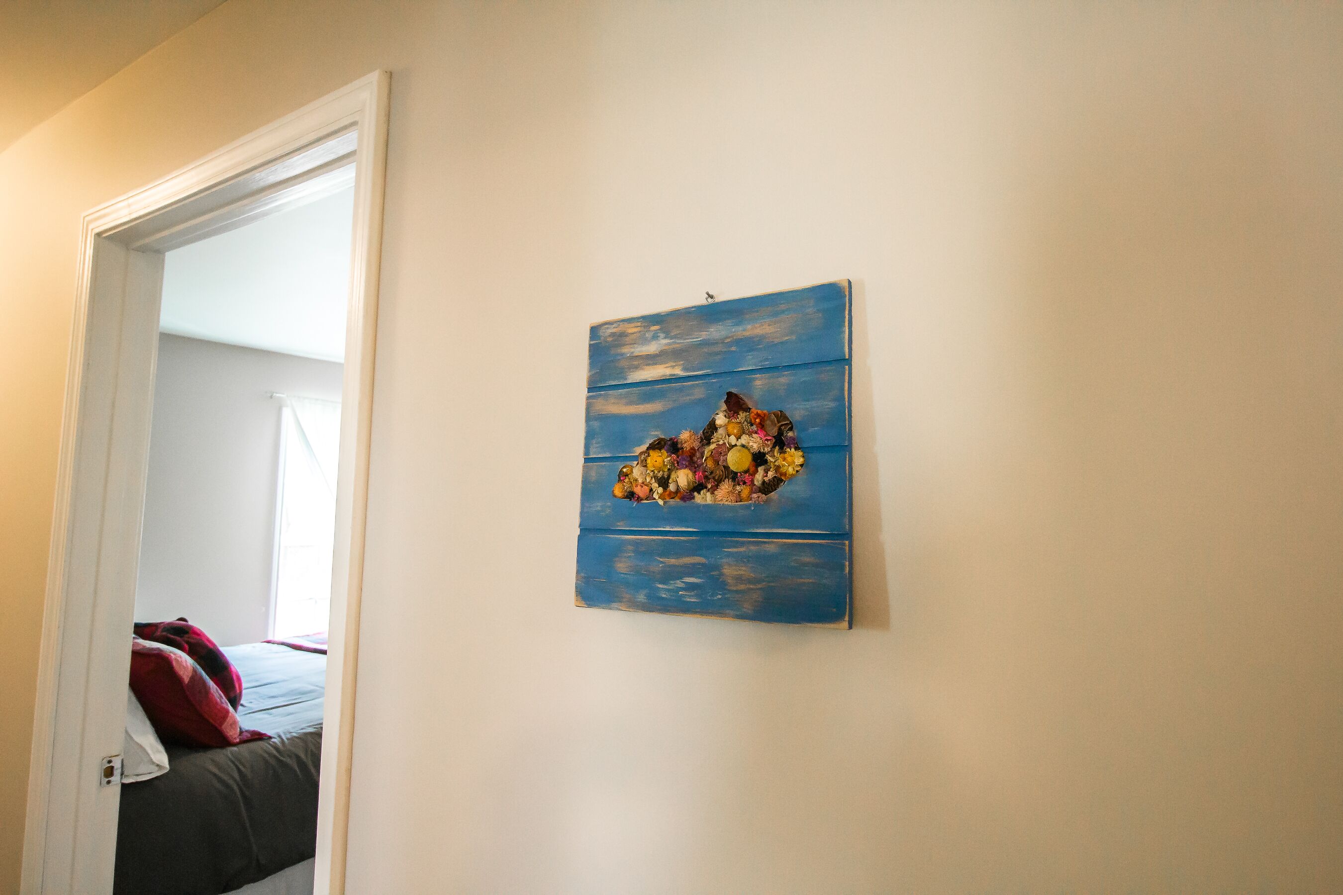 A bedroom with a bed, a door, and a wall-mounted artwork.