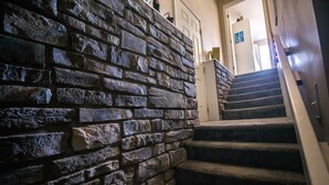 Una escalera con paredes de piedra y peldaños alfombrados que conducen a una puerta con la leyenda 'LAKE'.