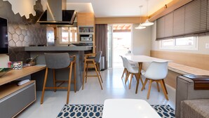 Een moderne keuken met een centraal eiland, barkrukken en een eethoek met witte stoelen.