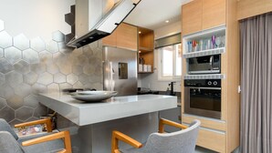 Een moderne keuken met een centraal eiland, houten stoelen en ingebouwde apparatuur.