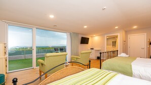 Habitación de hotel con dos camas, un ventanal con vistas, televisor de pantalla plana y balcón.
