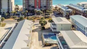 Un hôtel situé sur la côte, composé de plusieurs bâtiments, doté d’une piscine et offrant une vue sur la plage.