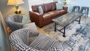 Un salon avec un canapé en cuir marron, des fauteuils à motifs, une table basse en bois et un tapis.