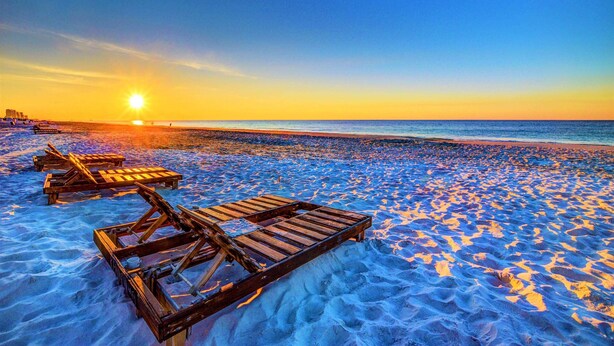 Une plage avec des transats et un coucher de soleil.