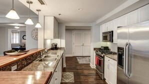 Una cocina moderna con encimera de granito, electrodomésticos de acero inoxidable y armarios blancos.