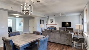 Una sala de estar moderna con comedor, chimenea, televisor y ventilador de techo.