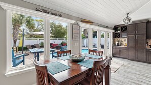 A spacious kitchen with a large dining area, a view of the backyard, and a pool.