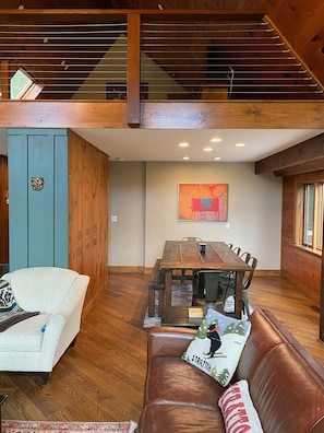 A spacious living area with a wooden ceiling, a dining table, and a leather couch.
