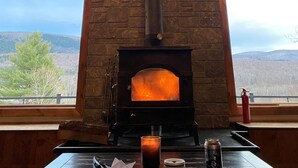 Una chimenea de piedra con una chimada, ventanas amplias y vistas a las montañas.