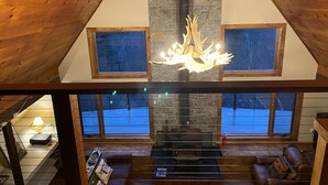 Habitación estilo loft con chimenea, vigas de madera y una araña.