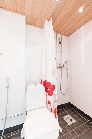 A bathroom with a shower, toilet, and a white sink.