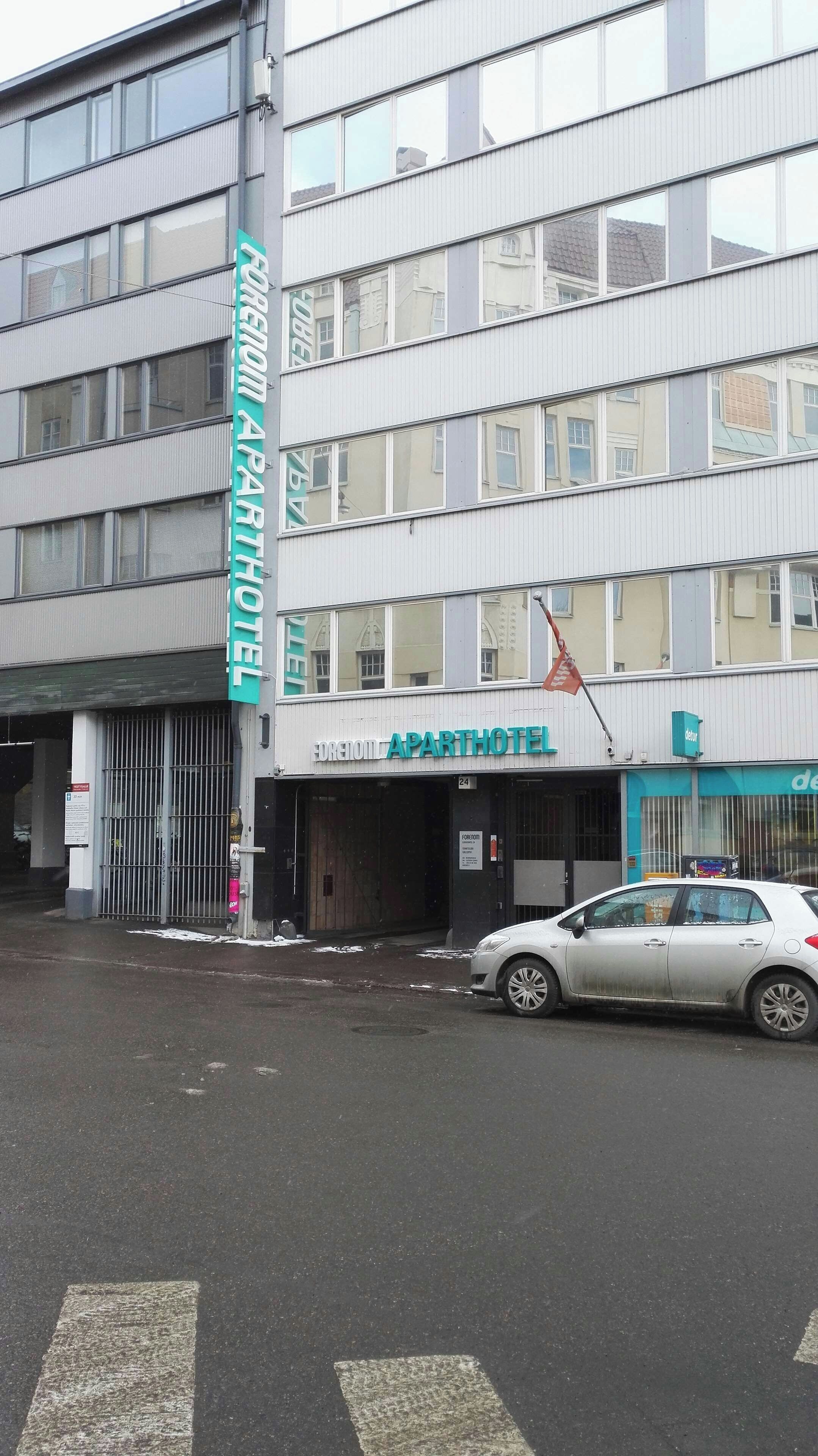 Un edificio con un cartel que dice 'EDREION APARTHOTEL' y un coche aparcado delante.