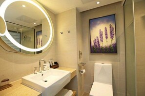 A modern bathroom with a large mirror, a sink, a toilet, and a shower.