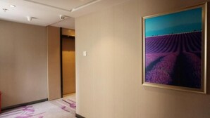 A hallway with a carpet featuring floral patterns, a framed painting of a purple landscape, and a door leading to another room. - Lavande Hotels Nanjing Xinjiekou Zhangfuyuan Metro Station (Nanjing)