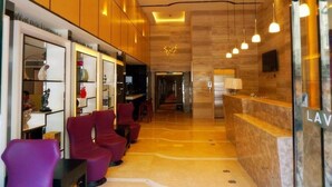 A hotel lobby with a reception desk, purple chairs, a reception area, and a hallway leading to other rooms. - Lavande Hotels Nanjing Xinjiekou Zhangfuyuan Metro Station (Nanjing)
