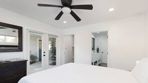 A bedroom with a large bed, a ceiling fan, and a dresser.