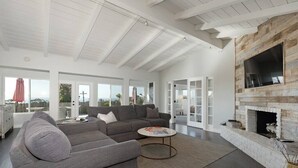 A spacious living room with a large gray sectional sofa, a round coffee table, and a stone fireplace.