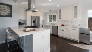 A modern kitchen with white cabinetry, stainless steel appliances, and a central island.