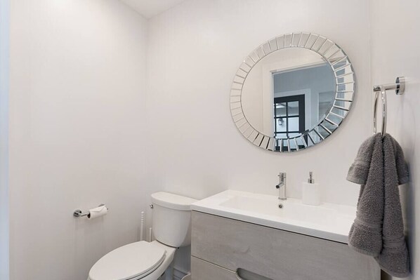 Ein modernes Badezimmer mit Toilette, Waschbecken und Spiegel.
