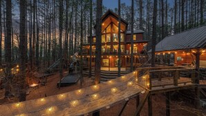 Uma cabana de madeira com vários níveis, um deck de madeira e uma ponte de corda.