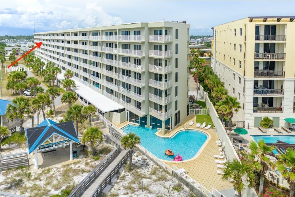 Un hotel de varios pisos con zona de piscina, que incluye una terraza solárium y sillones de descanso.