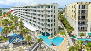 A multi-story hotel with a pool area, including a sun terrace and lounge chairs. - Beachfront Condo, Gulf Views, Sunset Balcony, Okaloosa Island (Fort Walton Beach)
