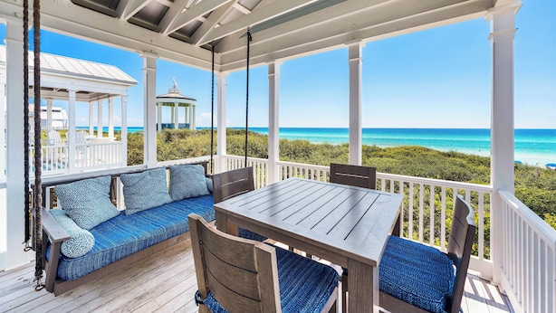 A covered outdoor area with a wooden table and benches, overlooking a beach. - Seaside's Chic Gulf-Front Retreat, Renovated with Elegant Design, Ocean Views, and Jacuzzi! (Santa Rosa Beach)