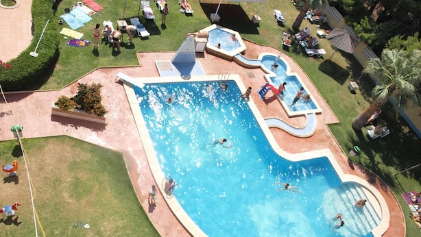 Vista aérea de una zona de piscina con varias piscinas y tumbonas.