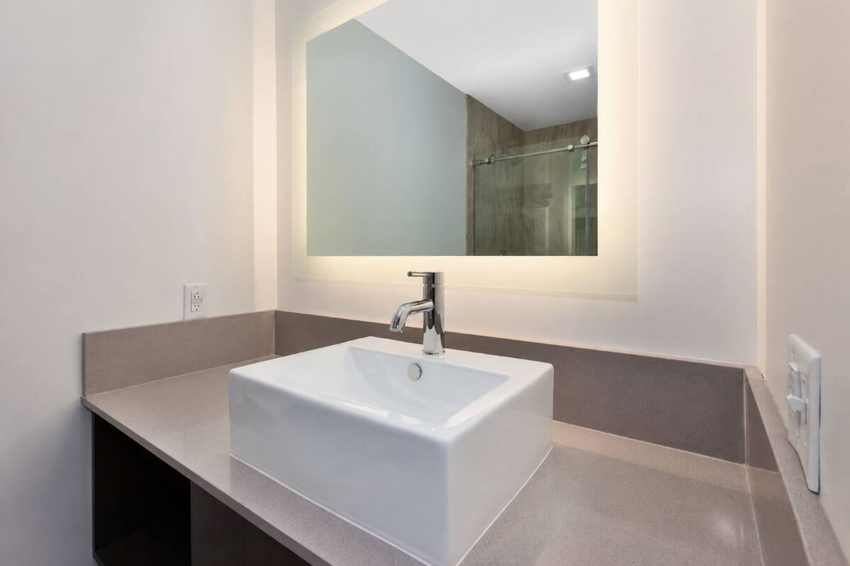 A bathroom with a white sink, a mirror, and a shower area.