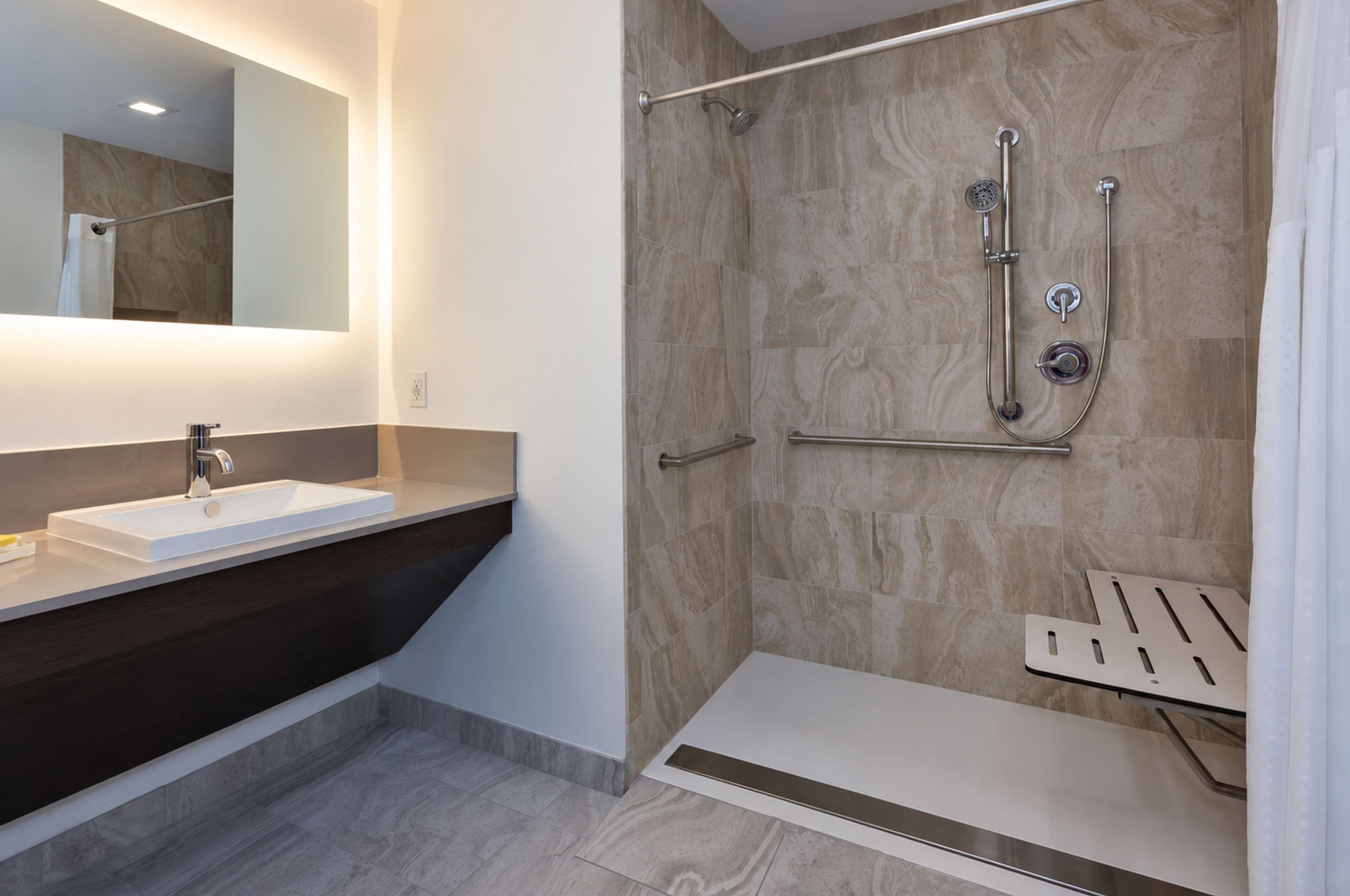 Een moderne badkamer met een witte wasbak, een douche met een handdouche en een handdoekhouder.