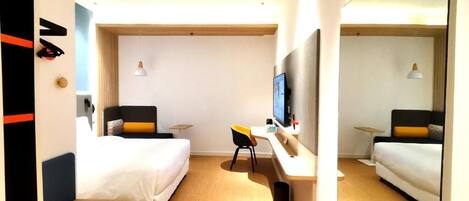 Quarto de hotel com duas camas, uma escrivaninha, uma TV e uma mesinha.