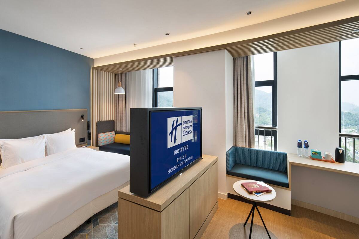 A hotel room with a bed, a TV, a seating area, and a window with a view.