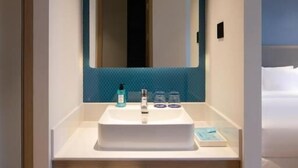 A modern bathroom with a white sink, a blue-tiled wall, and a large mirror. There are two white towels hanging on a rack below the sink. - Holiday Inn Express Shenzhen North Station by IHG (Shenzhen)