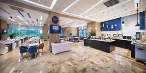 A modern hotel lobby with a breakfast bar, seating area, and a view of greenery outside. - Holiday Inn Express Shenzhen North Station by IHG (Shenzhen)